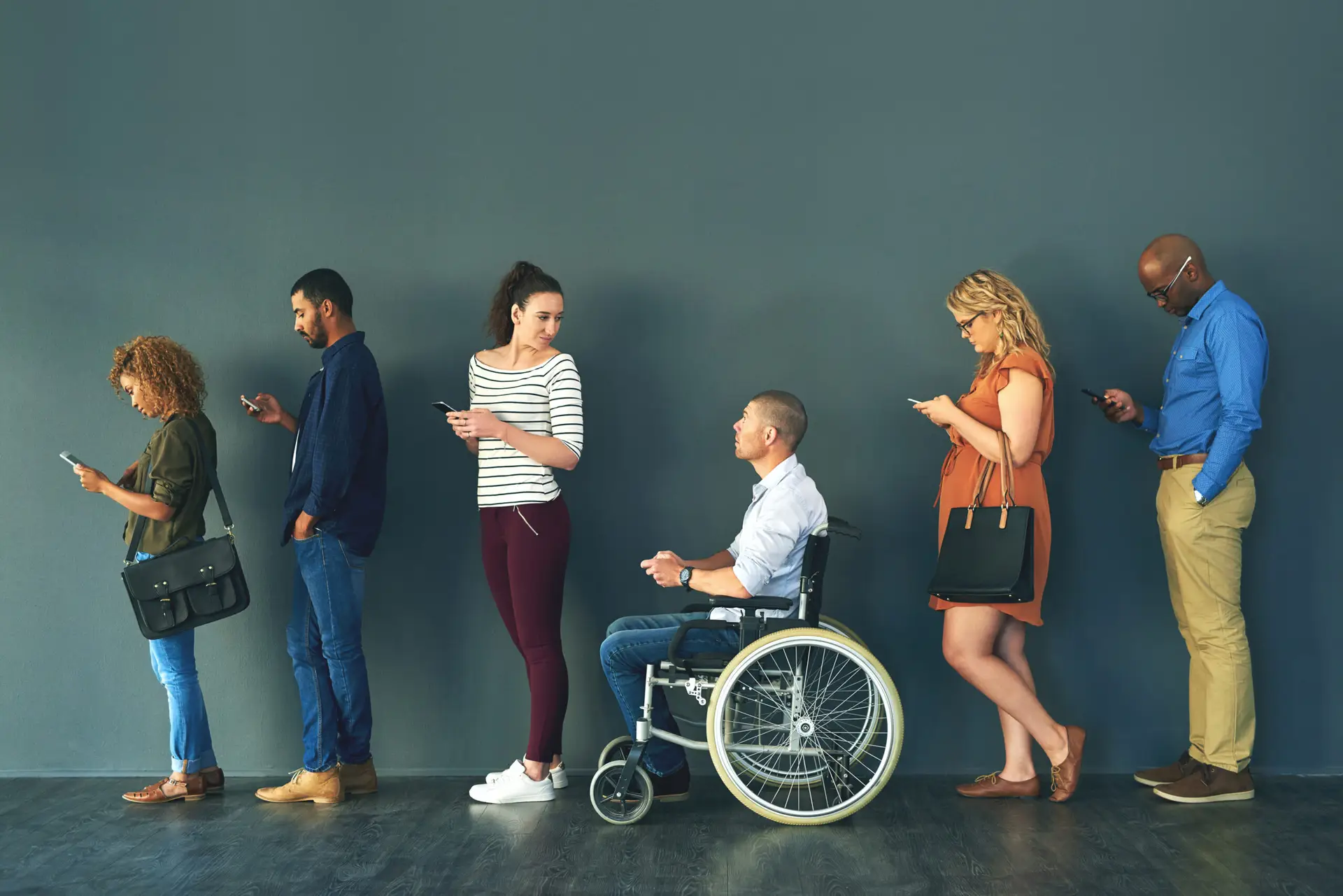 Hiring, inclusive and job interview with row of people in studio on gray background for opportunity. Diversity, human resources or recruitment and man with disability in wheelchair for equality.