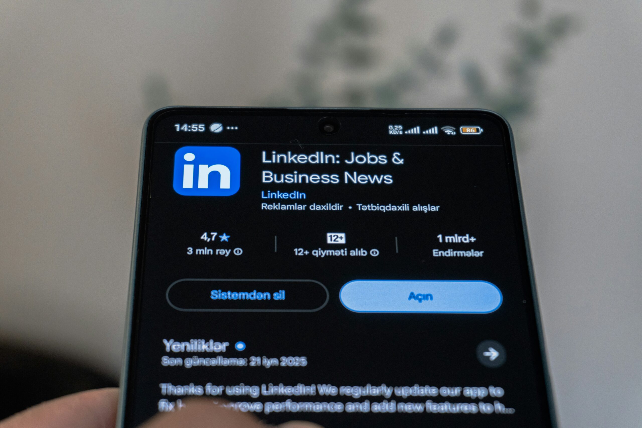 Ecran de smartphone afișând pagina aplicației LinkedIn în magazinul de aplicații, în modul întunecat.