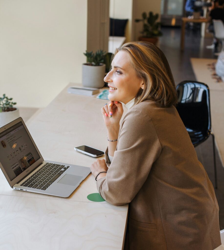 Femeie așezată la birou în fața unui laptop