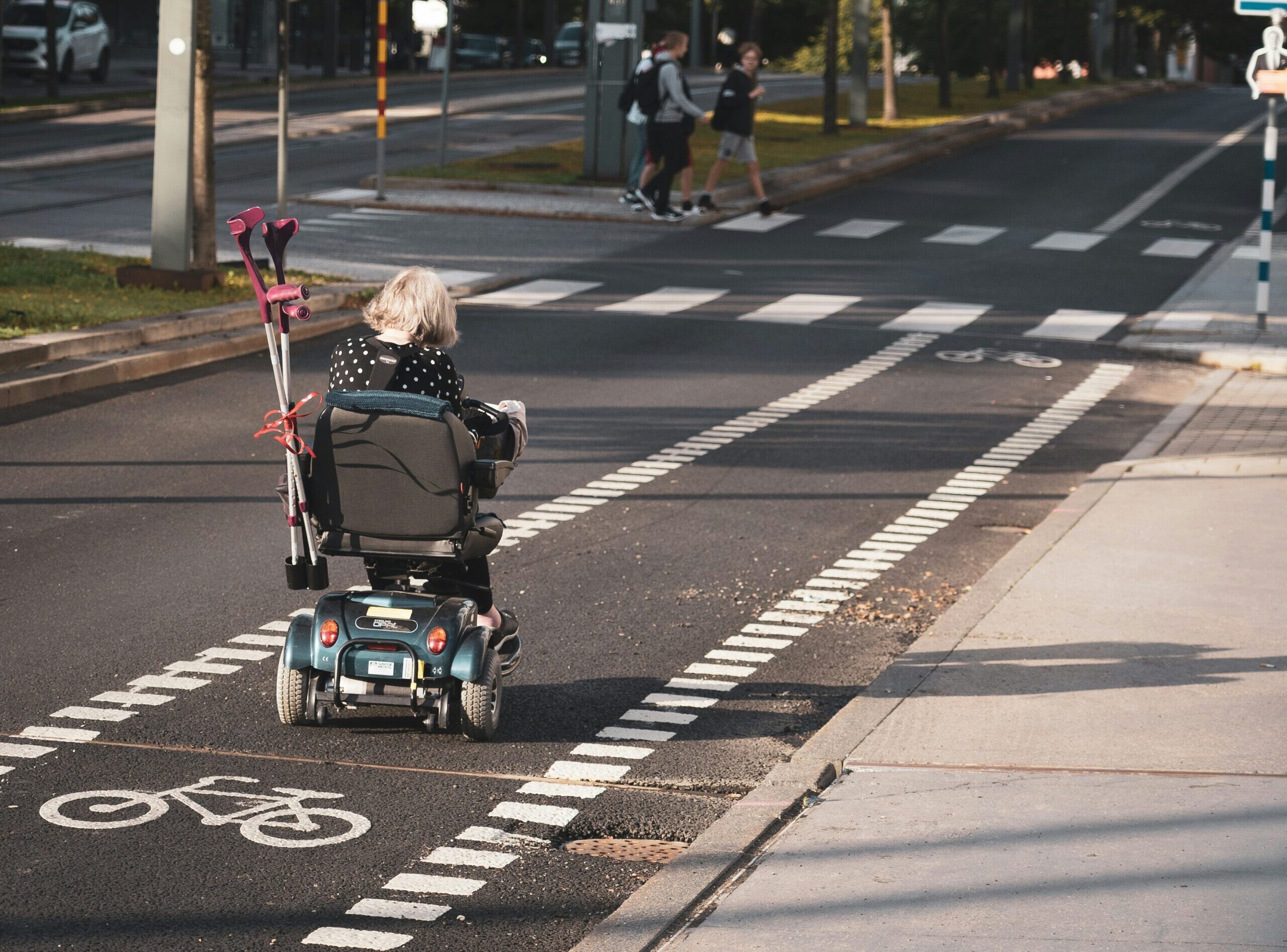 Femeie în scaun rulant se deplasează pe stradă.