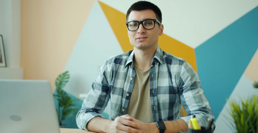 Bărbat așezat la birou, în fața unui laptop