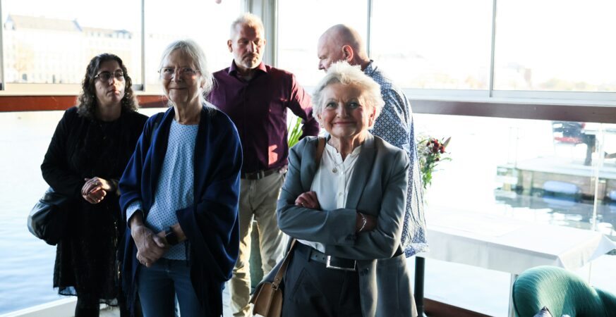 Un grup de angajați seniori pozează zâmbind într-un birou modern.