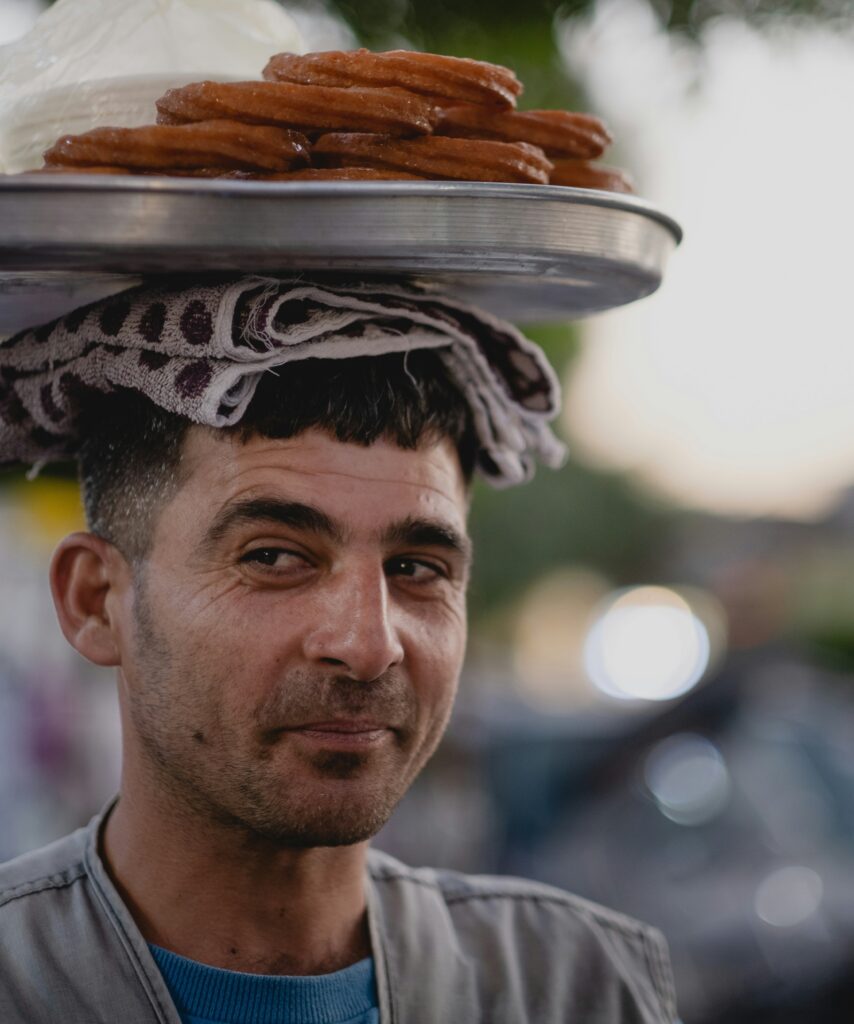 Un bărbat turc purtând pe cap o tavă cu dulciuri tradiționale. 